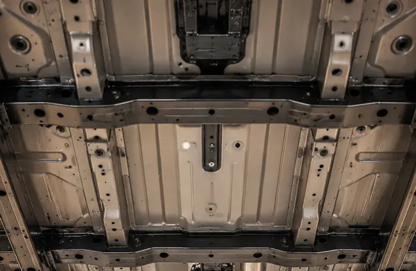 Clean late-model vehicle underside on a shop lift with visible factory underbody surfaces.