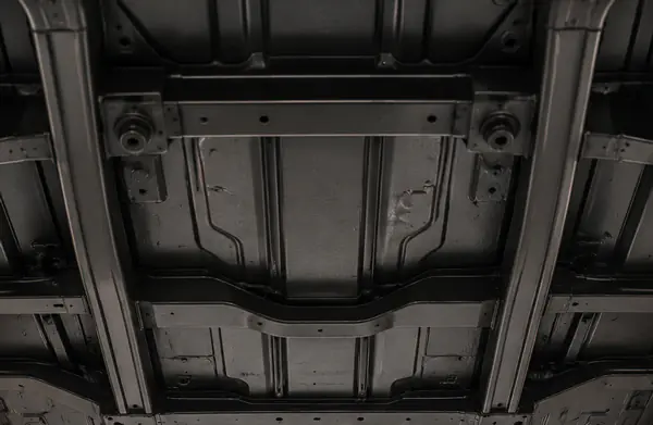 Clean vehicle underside on a shop lift with a refined satin-black protective underbody finish.
