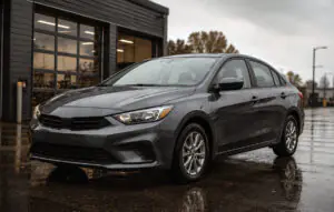 New clean everyday sedan on a wet road outside an automotive shop, representing daily driver undercoating protection.