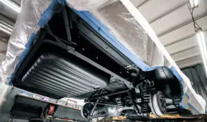 Restored vehicle underside with clean black underbody protection applied during a restoration project.
